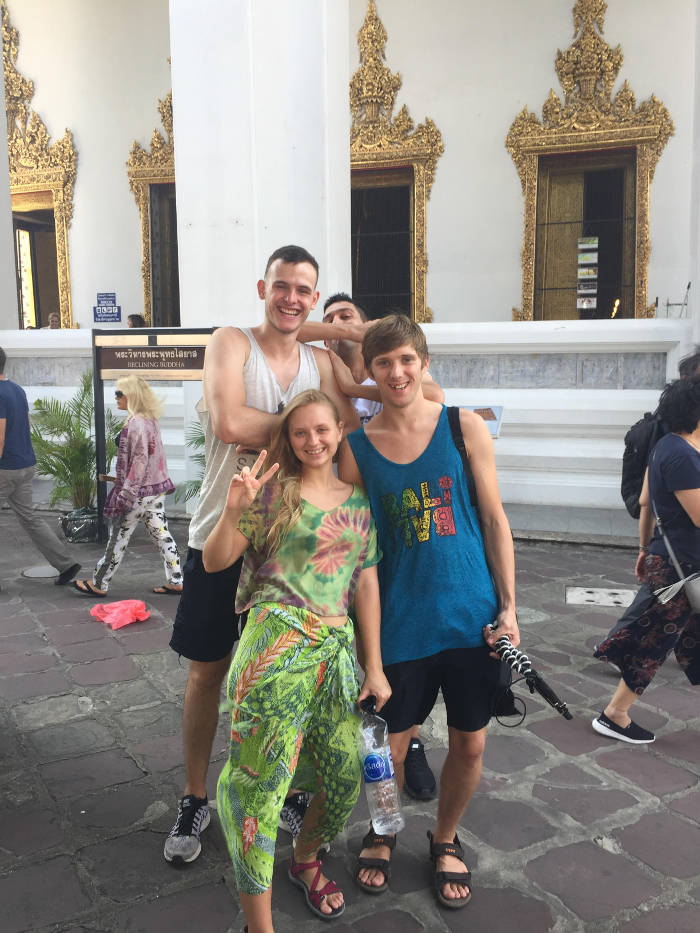 Foto van een groep backpackers die bij de Wat Pho boeddha in Bangkok staan.