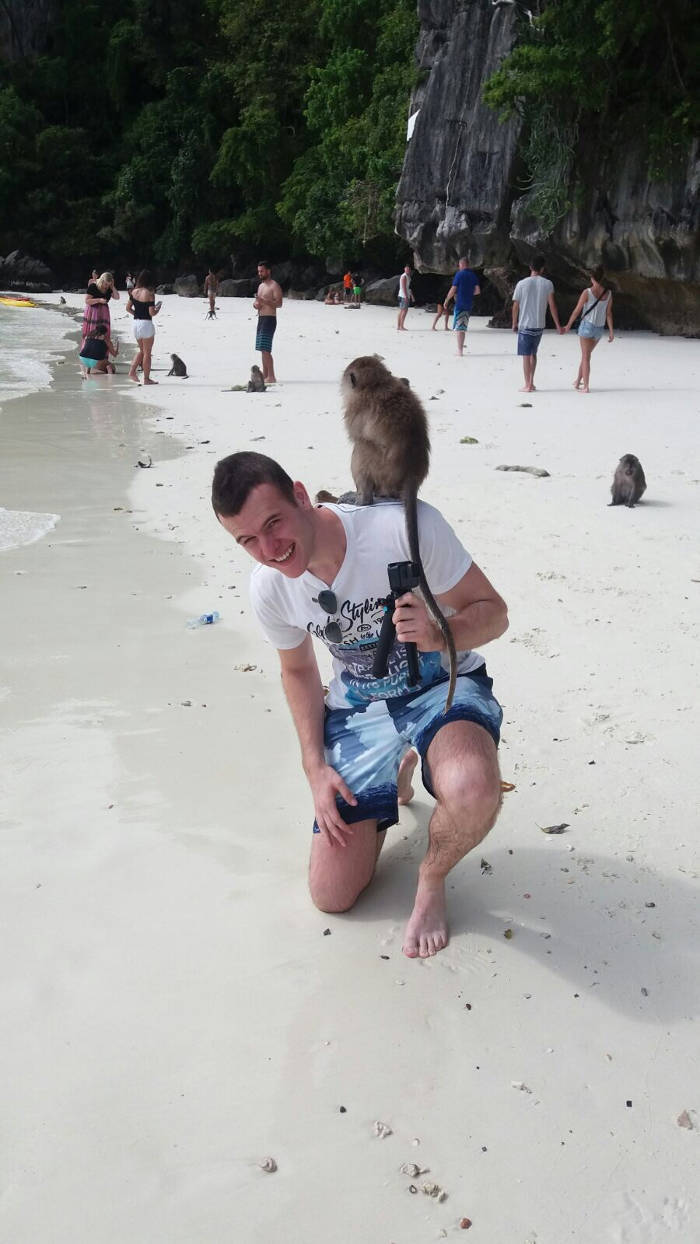Afbeelding van een jonge backpacker met een aapje op zijn schouder op de Monkey Beach nabij Koh Phi Phi.