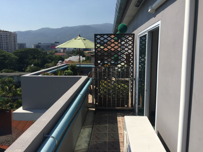 Foto van een balkon van een studio in Chiang Mai waarbij het balkon van de buren zichtbaar is.